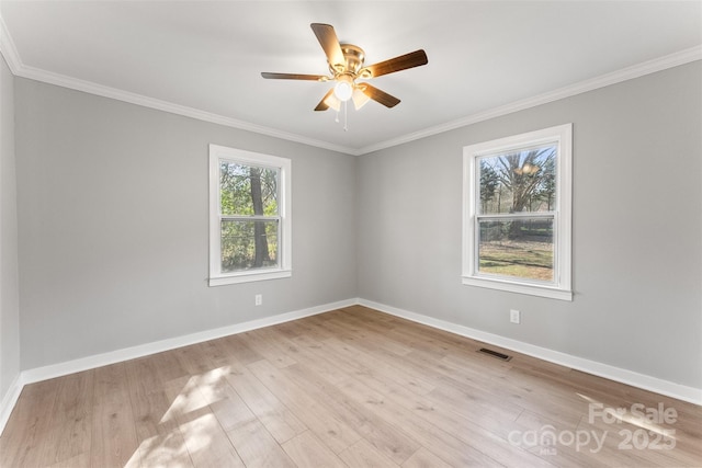 spare room featuring visible vents, ornamental molding, a ceiling fan, light wood finished floors, and baseboards