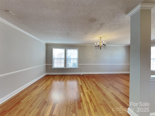 spare room featuring baseboards, light wood-type flooring, a chandelier, and ornamental molding