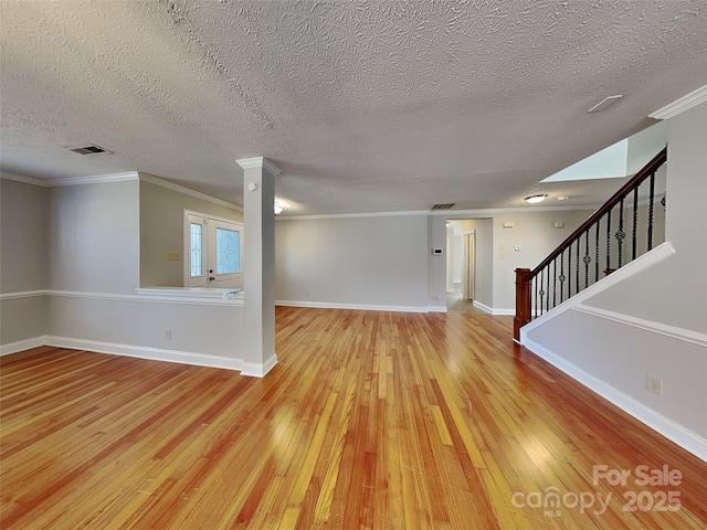 unfurnished room with visible vents, baseboards, stairs, light wood-style floors, and crown molding