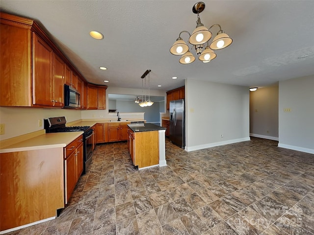 kitchen with a sink, a kitchen island, appliances with stainless steel finishes, an inviting chandelier, and baseboards