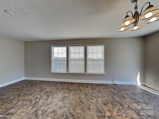 spare room with a notable chandelier, baseboards, and a textured ceiling