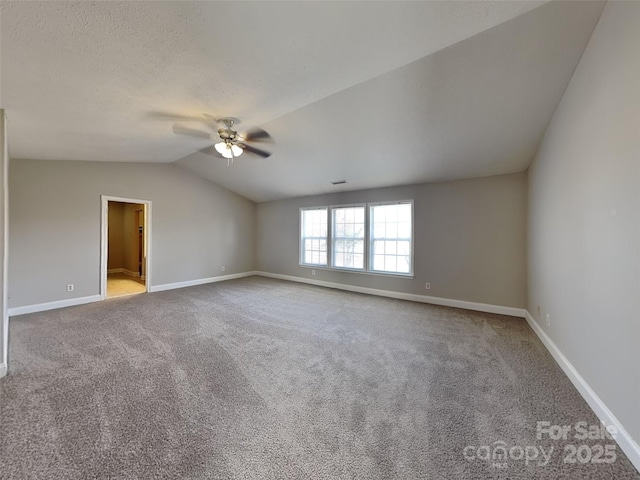 unfurnished room with carpet flooring, ceiling fan, baseboards, and vaulted ceiling