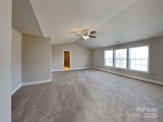 empty room featuring baseboards, lofted ceiling, ceiling fan, and carpet flooring