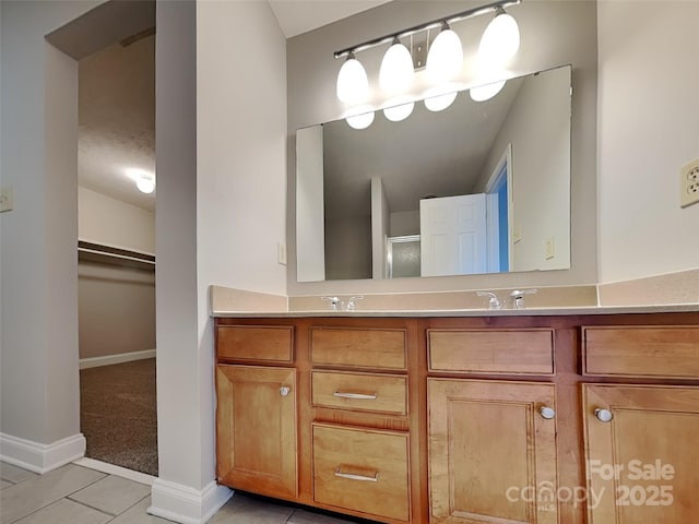 bathroom featuring tile patterned floors, a walk in closet, a shower with door, a sink, and double vanity