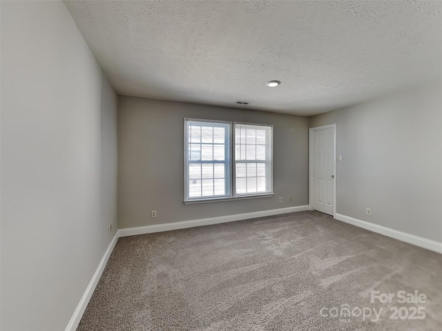 unfurnished room featuring visible vents, baseboards, carpet, and a textured ceiling