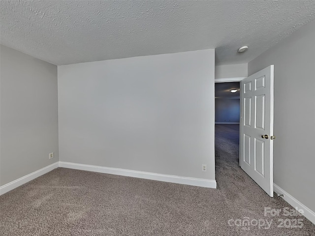 empty room with carpet flooring, a textured ceiling, and baseboards