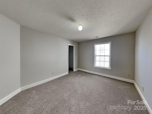 carpeted spare room featuring baseboards and a textured ceiling