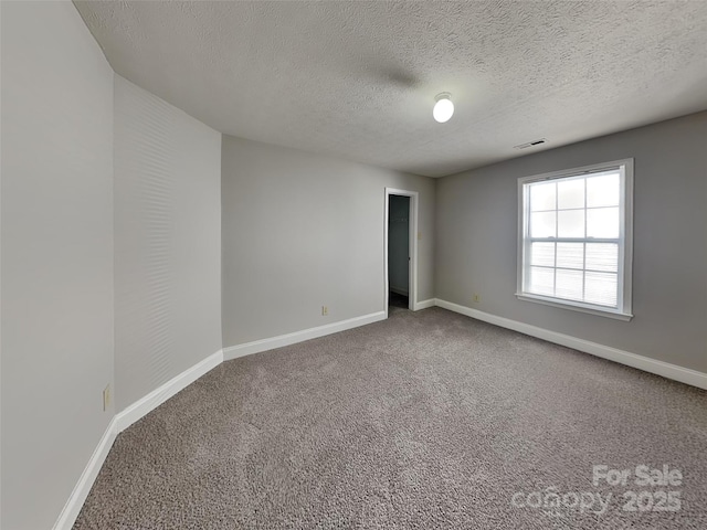 unfurnished room featuring visible vents, a textured ceiling, baseboards, and carpet