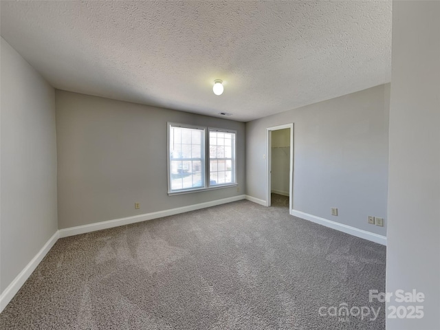 unfurnished room with visible vents, baseboards, carpet, and a textured ceiling