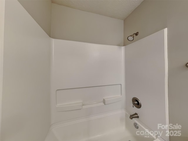 bathroom with a textured ceiling and washtub / shower combination