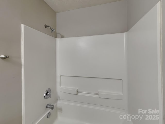 full bath with bathtub / shower combination and a textured ceiling