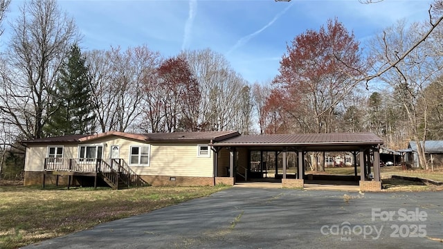 manufactured / mobile home featuring an attached carport, a front yard, metal roof, crawl space, and driveway