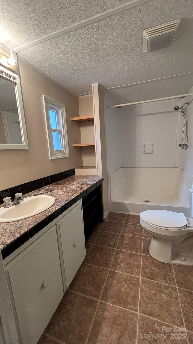 bathroom with vanity, walk in shower, tile patterned flooring, a textured ceiling, and toilet