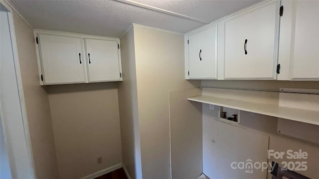 laundry area featuring cabinet space, a textured ceiling, baseboards, and washer hookup