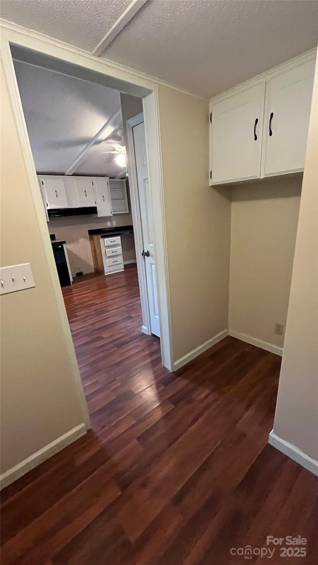 hall featuring baseboards, a textured ceiling, and dark wood-style floors