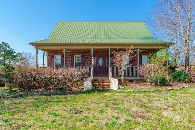 view of front facade with a porch, brick siding, a front yard, and metal roof