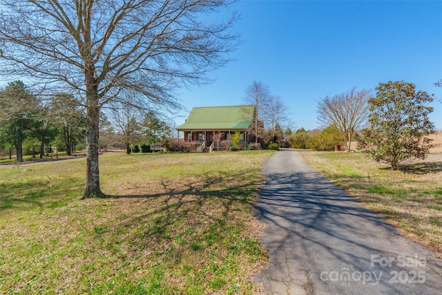 view of front facade with a front lawn, driveway, and metal roof