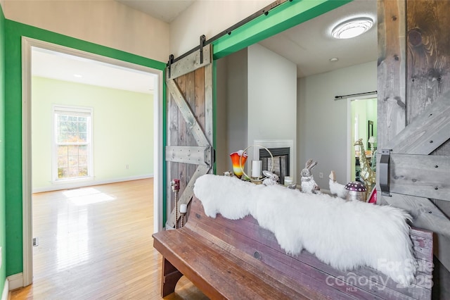 interior space with a barn door, wood finished floors, and baseboards