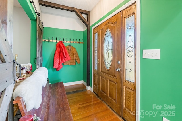 foyer featuring a barn door, baseboards, and wood finished floors