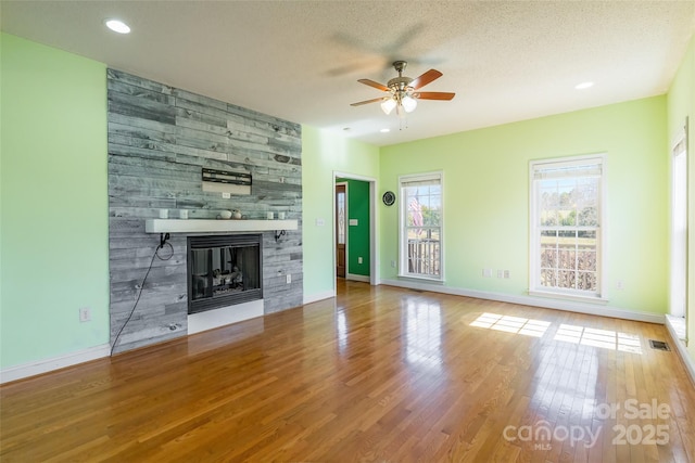 unfurnished living room with baseboards, a fireplace, wood finished floors, and a ceiling fan