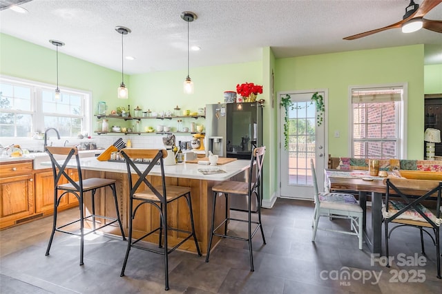 kitchen with backsplash, a kitchen island, light countertops, and a ceiling fan