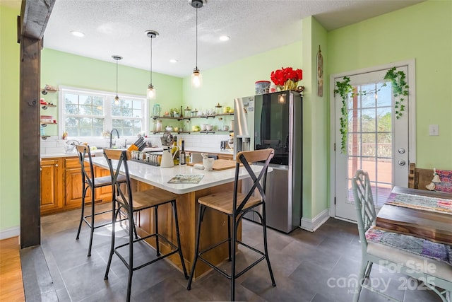 kitchen with tasteful backsplash, a kitchen island, brown cabinetry, stainless steel fridge with ice dispenser, and light countertops