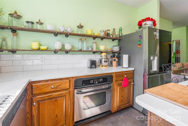 kitchen with open shelves, appliances with stainless steel finishes, brown cabinetry, light countertops, and decorative backsplash