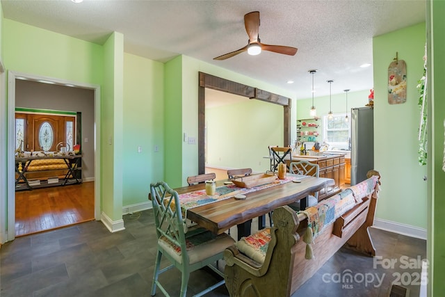 dining area with baseboards, a textured ceiling, and a ceiling fan