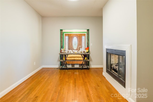 living area featuring light wood finished floors, a fireplace, and baseboards