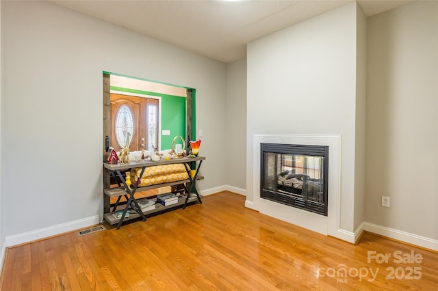 interior space featuring light wood-style floors, baseboards, and a multi sided fireplace