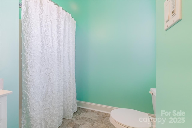 bathroom featuring a shower with shower curtain, baseboards, and toilet