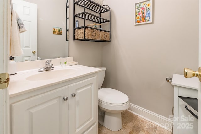 bathroom with vanity, toilet, and baseboards