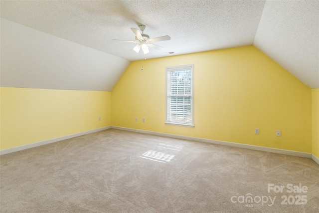 additional living space featuring a ceiling fan, visible vents, baseboards, a textured ceiling, and carpet flooring