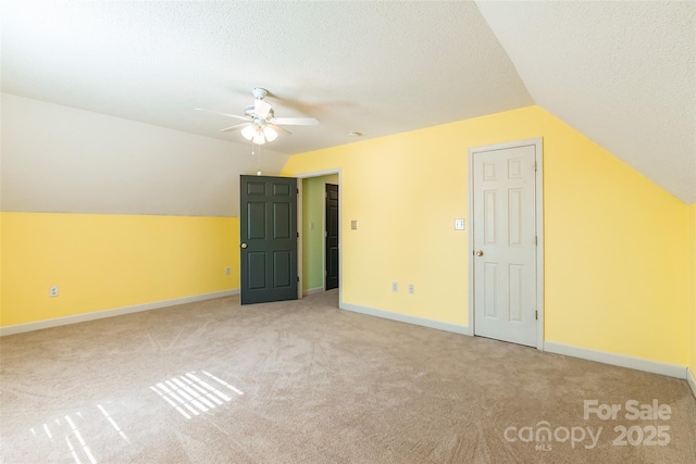 bonus room featuring baseboards, ceiling fan, lofted ceiling, light carpet, and a textured ceiling