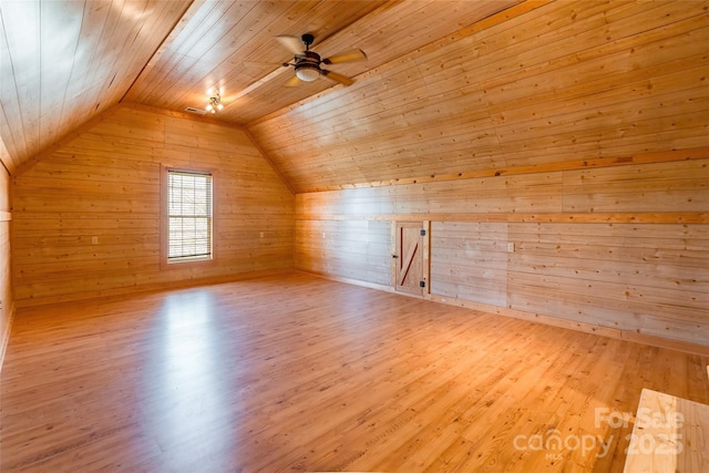 bonus room featuring wood finished floors, wooden walls, wooden ceiling, ceiling fan, and vaulted ceiling