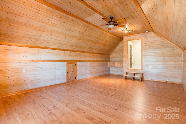 additional living space with a ceiling fan, wooden ceiling, wood finished floors, and wood walls