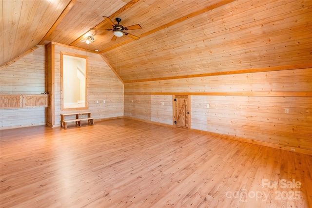 additional living space with wooden walls, a ceiling fan, wood finished floors, vaulted ceiling, and wood ceiling