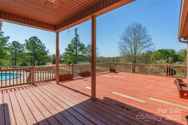 wooden deck with a ceiling fan and a fenced in pool