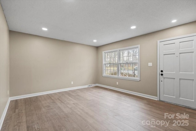 entryway with visible vents, baseboards, recessed lighting, wood finished floors, and a textured ceiling