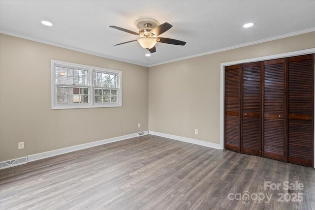 unfurnished bedroom featuring visible vents, ornamental molding, wood finished floors, a closet, and baseboards