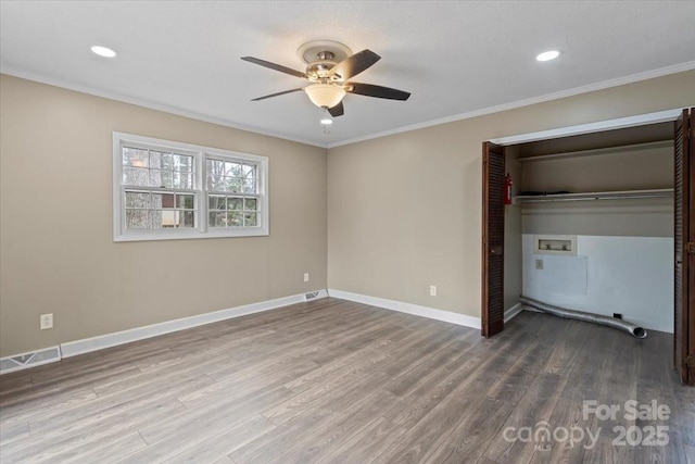 unfurnished bedroom featuring visible vents, baseboards, wood finished floors, and ornamental molding