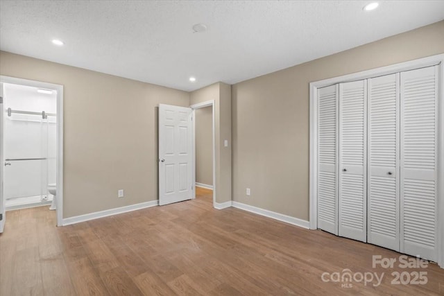 unfurnished bedroom with a closet, recessed lighting, baseboards, and wood finished floors