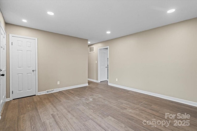 spare room featuring recessed lighting, wood finished floors, visible vents, and baseboards