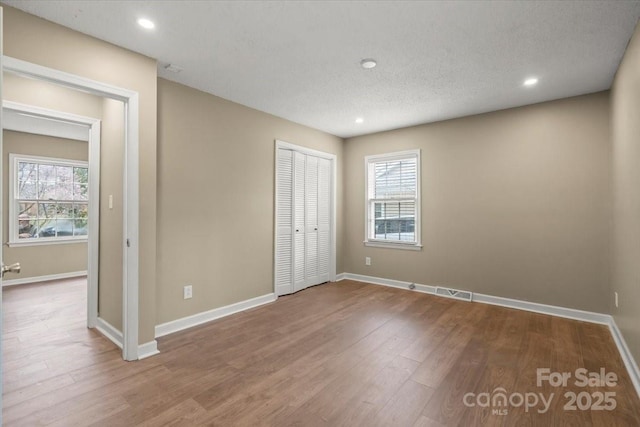 unfurnished bedroom featuring multiple windows, baseboards, and wood finished floors