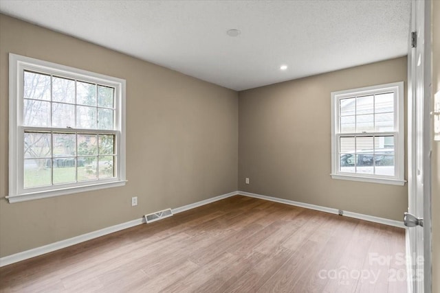 unfurnished room with visible vents, baseboards, a healthy amount of sunlight, and wood finished floors