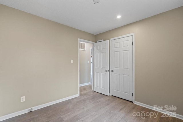 unfurnished bedroom featuring wood finished floors, visible vents, and baseboards