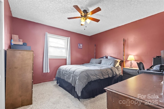 bedroom with light colored carpet, a ceiling fan, and a textured ceiling