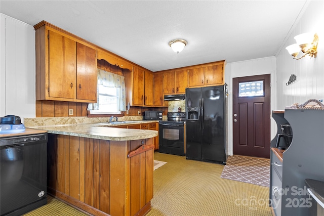 kitchen with a peninsula, black appliances, light countertops, under cabinet range hood, and brown cabinets