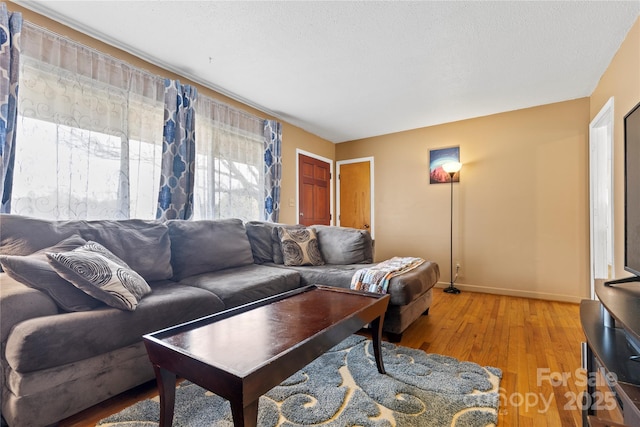 living area featuring baseboards, a textured ceiling, and light wood-style flooring