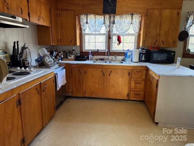 kitchen with a sink, under cabinet range hood, black microwave, and light countertops